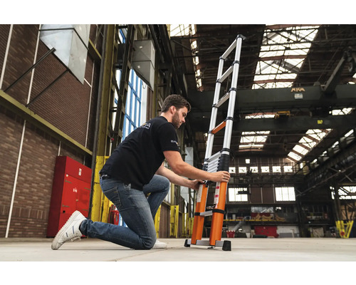 En person justerar en teleskopisk aluminiumstege i ett lager.