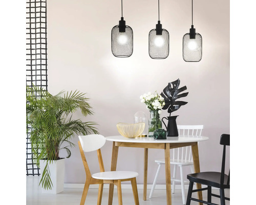 Matsal med matbord, stolar och tre svarta hänglampor