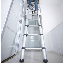 Person som klättrar på en utdragbar vindstrappa av aluminium i ett hus