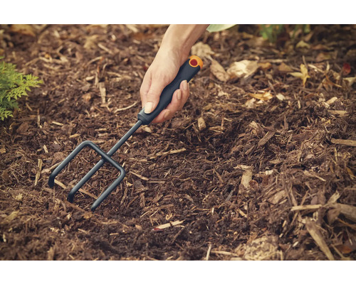 Person arbetar med en jordfräs i trädgårdsjorden.