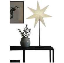 Dekorativ scen med stjärnlampa, växt och inramad bild på ett bord