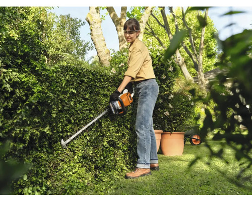 Kvinna klipper häck med häcksax i trädgården