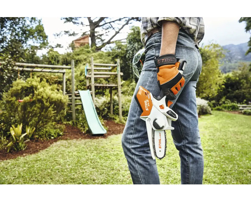 En person håller i en Stihl batteridriven motorsåg i trädgården.