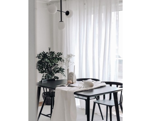 Matsal med svart bord, stolar, vit bordslöpare, växt och lampa