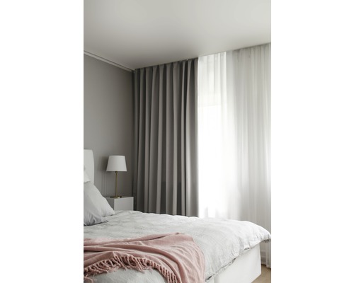 Sovrum med säng, sänglampa och gardiner