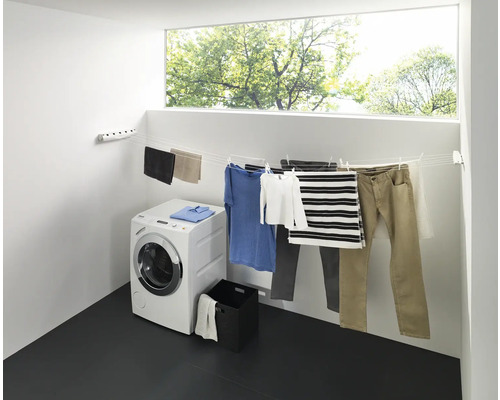 Torkställning med tvätt, tvättmaskin och fönster i ett ljust rum