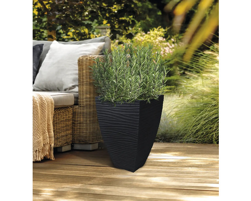Svart blomlåda med strukturmönster och grön växt på en träterrass