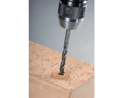 Borrmaskin borrar ett hål i en tegelsten.