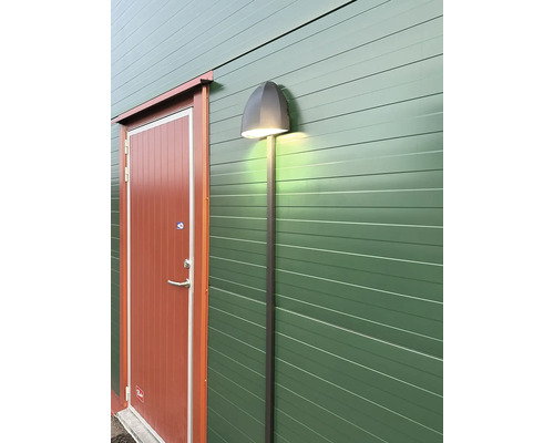 Utomhusfoto av en vägg med en dörr och en utomhuslampa monterad på den