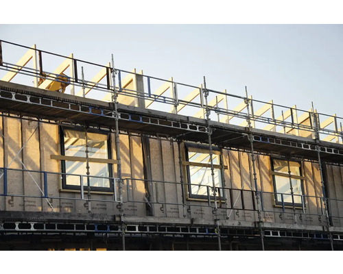 Råbyggnad av ett hus med byggnadsställning och fönster