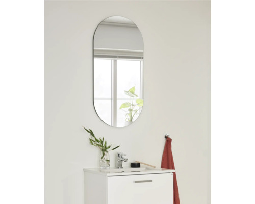 Oval spegel ovanför ett handfat i badrummet.