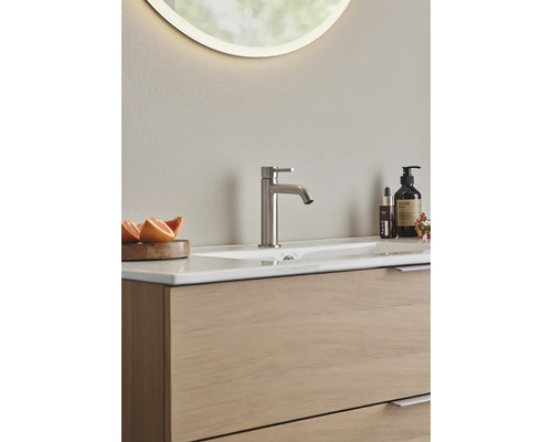 Badrum med handfat, blandare och belyst spegel