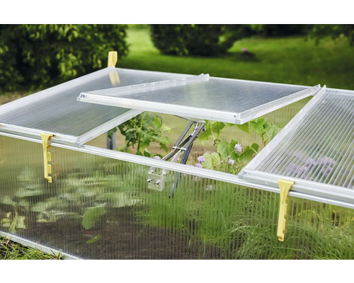 Odlingsbänk med transparenta väggar och öppnade fönster i trädgården