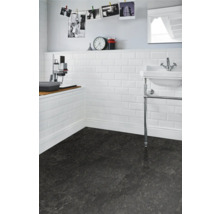 Badrum med vitt metrokakel på väggen och mörkt golv.