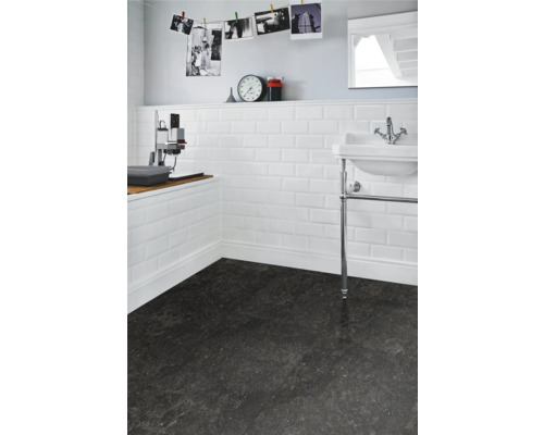 Badrum med vitt metrokakel på väggen och mörkt golv.