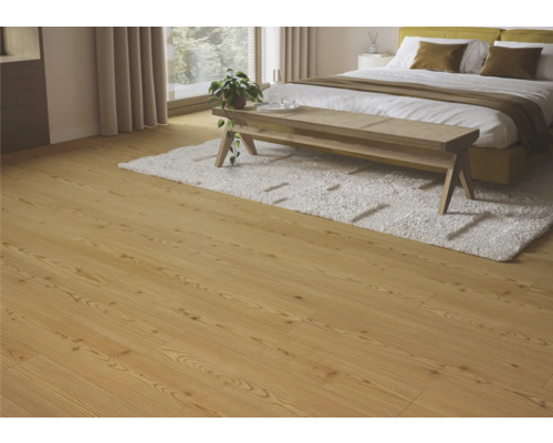 Ljust trägolv i ett sovrum med säng, matta och bänk