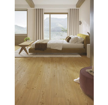 Ljust sovrum med säng, trägolv och utsikt över bergen.