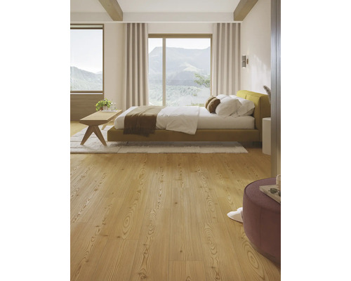 Ljust sovrum med säng, trägolv och utsikt över bergen.