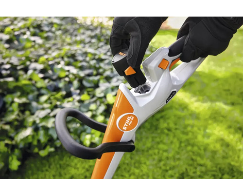 En person sätter in ett batteri i en sladdlös grästrimmer.