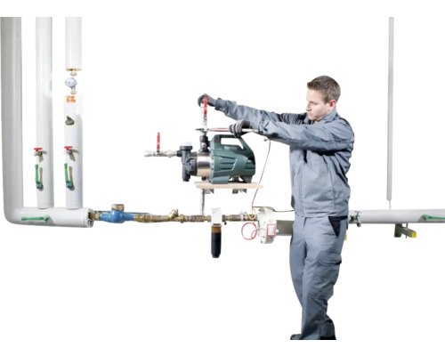 En installatör monterar en trädgårdspump på ett rörsystem.