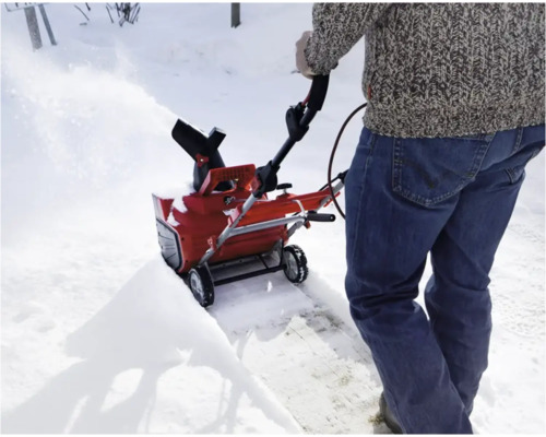 En person använder en snöslunga för att röja snö.