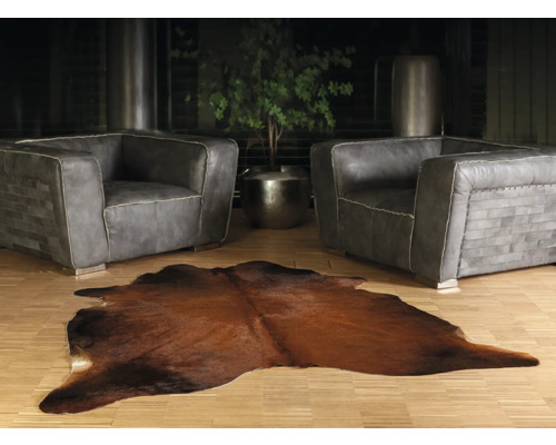 Vardagsrum med två grå läderfåtöljer och en brun kohudmatta