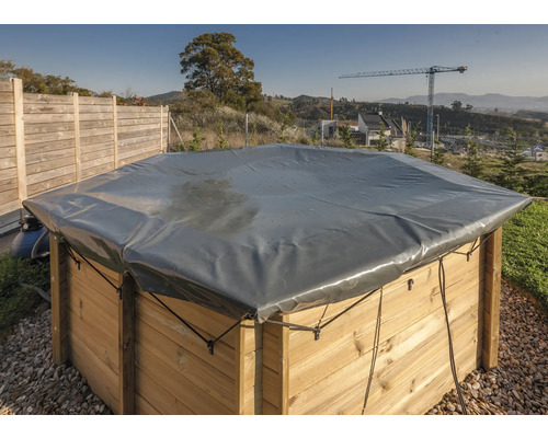 Täckt pool med träpanel och grå presenning utomhus