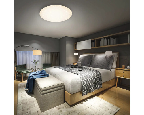 Sovrum med säng, sängbord, bänk, matta och taklampa