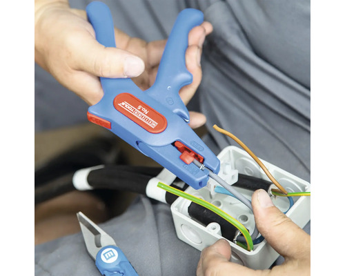 Elektriker använder en avisoleringstång för att bearbeta kablar i en kopplingsdosa.