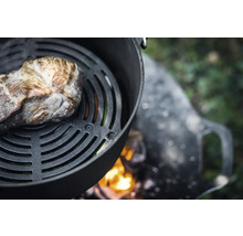 Köttbit på grillgaller över öppen eldstad