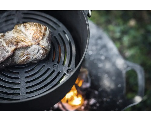 Köttbit på grillgaller över öppen eldstad