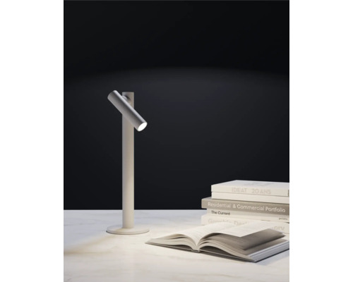 Bordslampa bredvid en trave böcker och en öppen bok