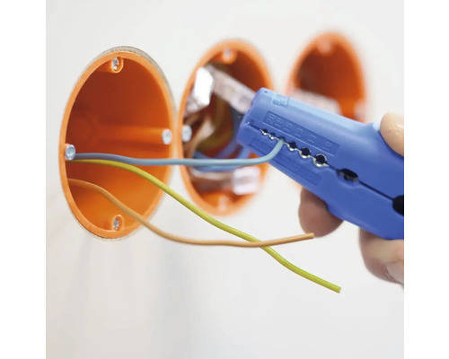 En elektriker tar bort isoleringen från en kabel med en avisoleringstång nära en kopplingsdosa.