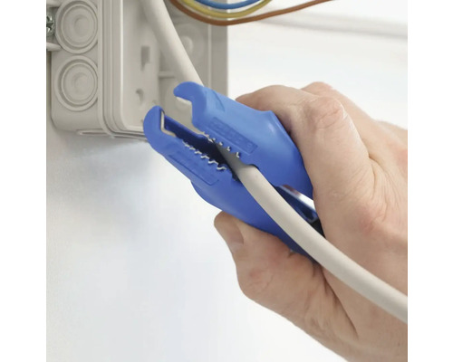 En person använder en blå avbitartång för att bearbeta en kabel bredvid en kopplingsdosa.