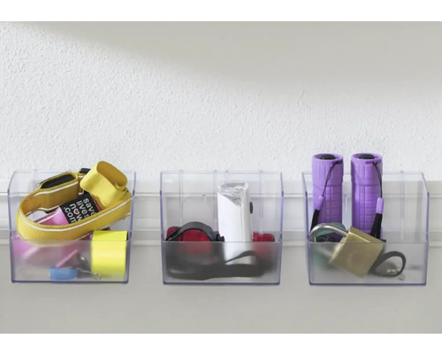 Tre transparenta förvaringslådor med diverse föremål fästa på en vägg