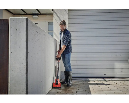 Man rengör en betongvägg med en elektrisk borste utomhus