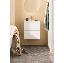 Ljust badrum med vitt tvättställsskåp, spegel och mönstrade golvplattor