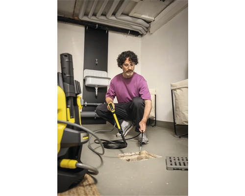 Man rengör avlopp med rörrengöringssats och högtryckstvätt i källaren.