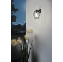 Vägglampa med geometrisk lampskärm och blomdekoration.