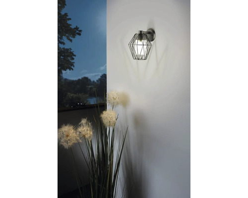 Vägglampa med geometrisk lampskärm och blomdekoration.