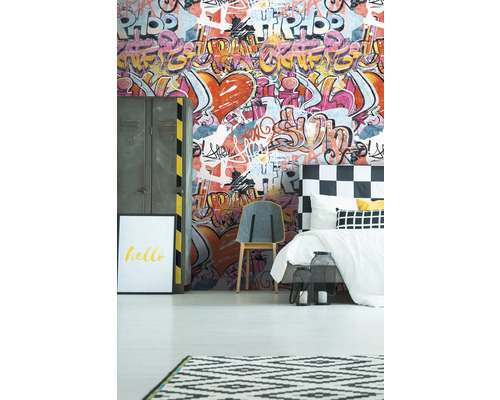 Ett sovrum med graffititapet, säng, stol och dekorationer.