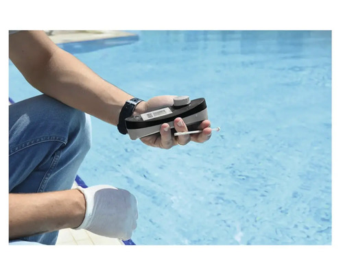 En person mäter vattenkvaliteten i en pool med en pooltestare.