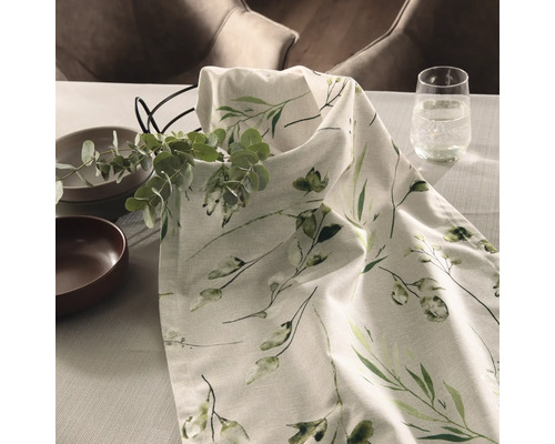 Bordsdekoration med bordslöpare, porslin, glas och eukalyptusgrenar på ett bord