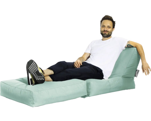 Man kopplar av på en mintgrön sittsäckssoffa