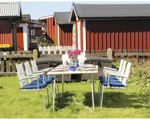 Dukat trädgårdsbord med stolar utomhus framför trähus