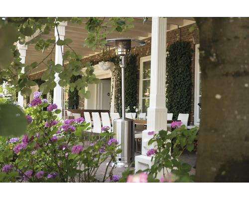 Terrass med terrassvärmare, bord och stolar i trädgården