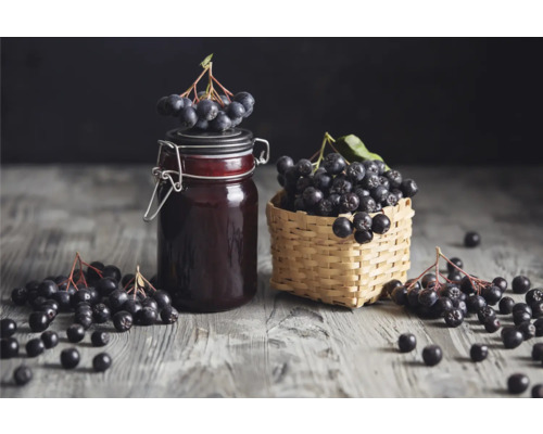 Aronia i en glasburk och korg på ett bord