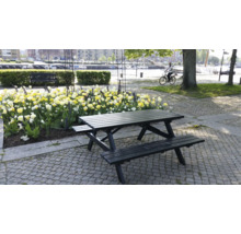 Picknickbord i trä i park med blomsterrabatter och en person på cykel