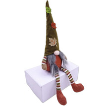 Dekorativ tomte med mössa och höstlöv sitter på en låda