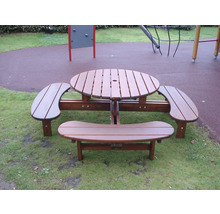 Runt picknickbord av trä med integrerade bänkar på en lekplats.